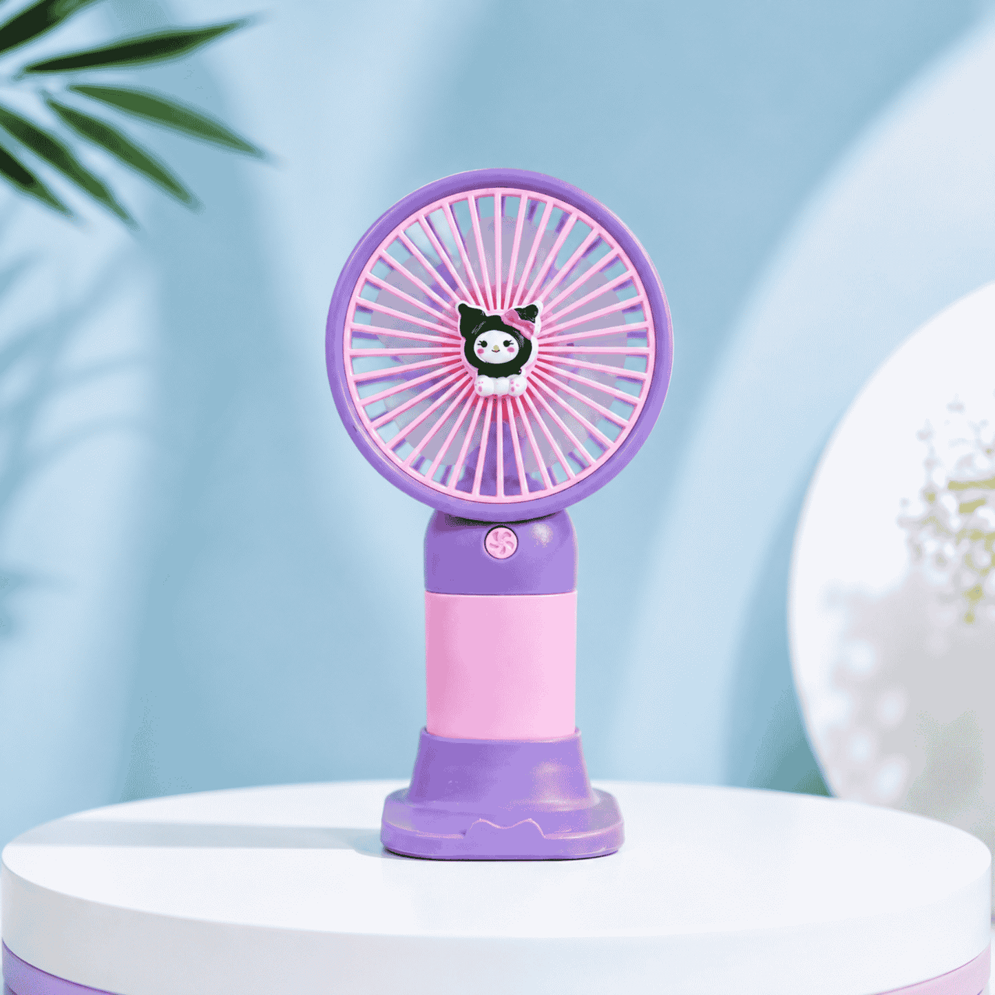 Purple and pink handheld fan on a white surface with a light blue background
