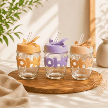Three glass tumblers with colorful lids and 'OHO' text on a wooden tray.