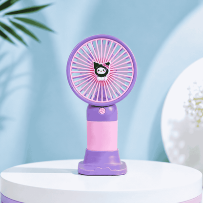 Purple and pink handheld fan on a white surface with a light blue background