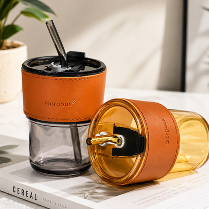 Gold and black aesthetic glass coffee tumblers with reusable straws displayed on modern tabletop setup